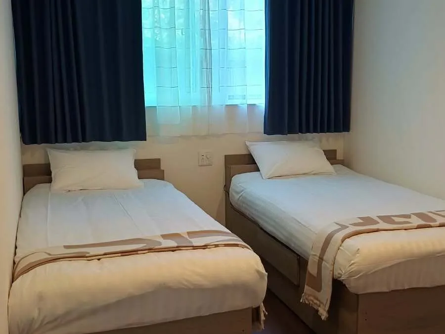 Twin single beds with navy curtains in a Yukiyama Apartment bedroom