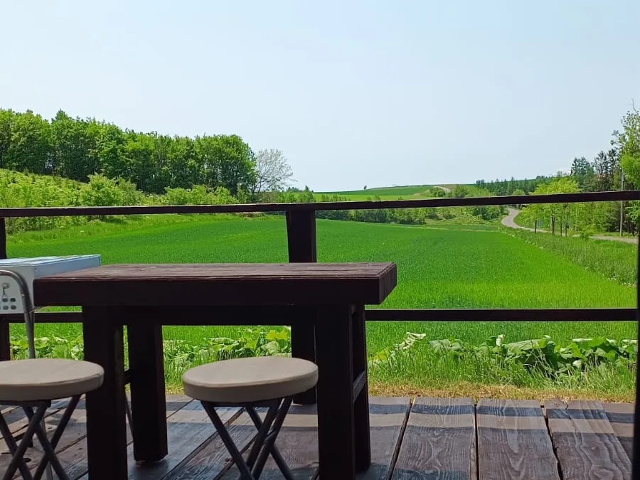 Deck table and stools overlooking green fields
